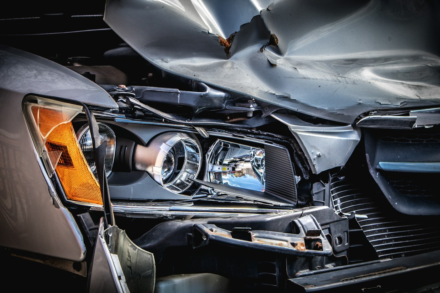 The crushed front of a silver car after a collision